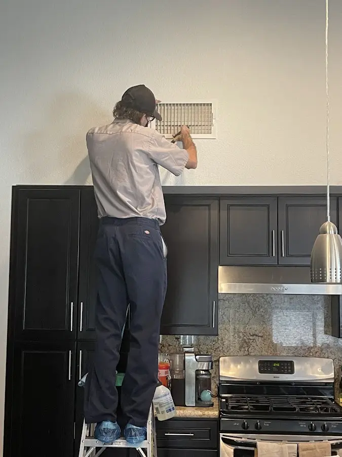 Technician inspecting an air vent during HVAC service in Greenwood
